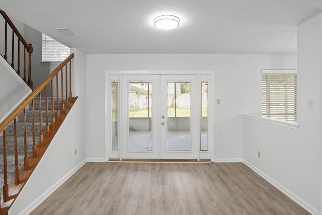 doorway to outside featuring french doors, a textured ceiling, and light hardwood / wood-style floors