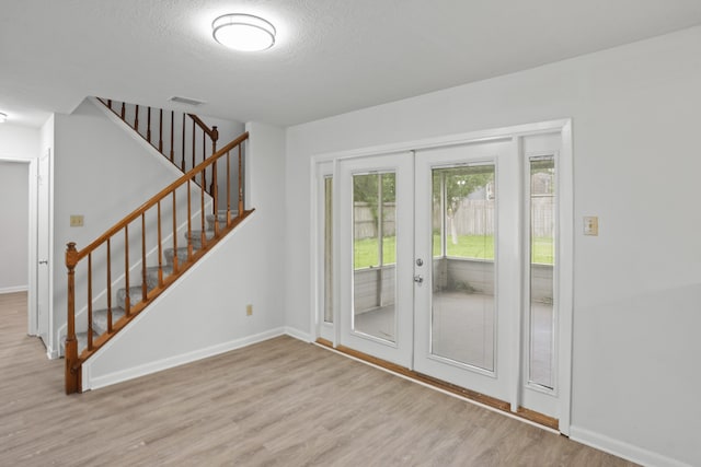 entryway featuring french doors, a textured ceiling, and light wood-type flooring