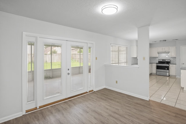 interior space with french doors, a textured ceiling, and light hardwood / wood-style flooring