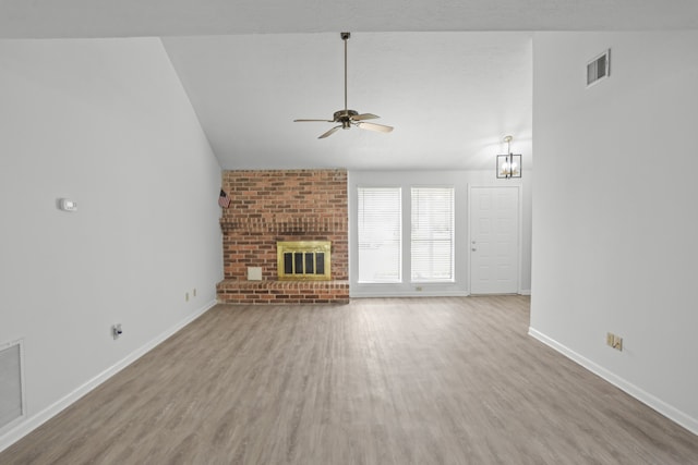 unfurnished living room featuring vaulted ceiling, a brick fireplace, wood-type flooring, and ceiling fan