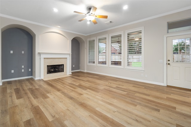 unfurnished living room featuring ornamental molding, light wood-type flooring, and a wealth of natural light