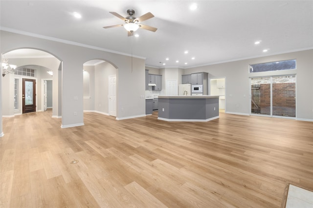 unfurnished living room with crown molding, light wood-type flooring, and ceiling fan with notable chandelier