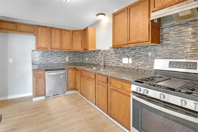 kitchen with decorative backsplash, light wood-type flooring, dark stone counters, stainless steel appliances, and sink