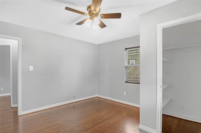 unfurnished bedroom featuring a walk in closet, dark hardwood / wood-style flooring, a closet, and ceiling fan