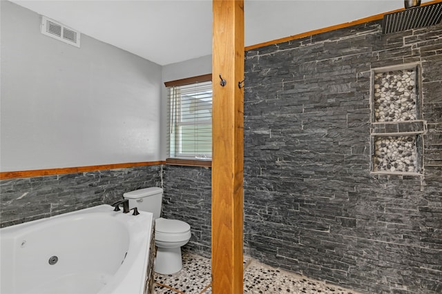 bathroom featuring a bath, toilet, tile walls, and tile patterned floors