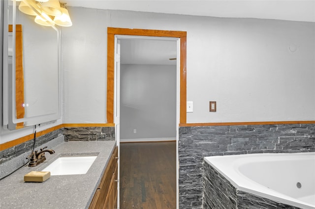 bathroom featuring hardwood / wood-style floors, vanity, and a relaxing tiled tub