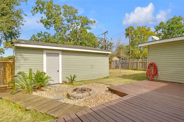 wooden deck with a yard, a shed, and an outdoor fire pit