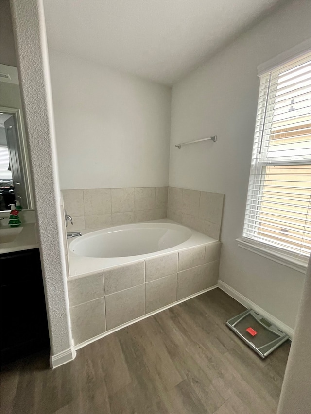 bathroom with tiled tub and hardwood / wood-style flooring