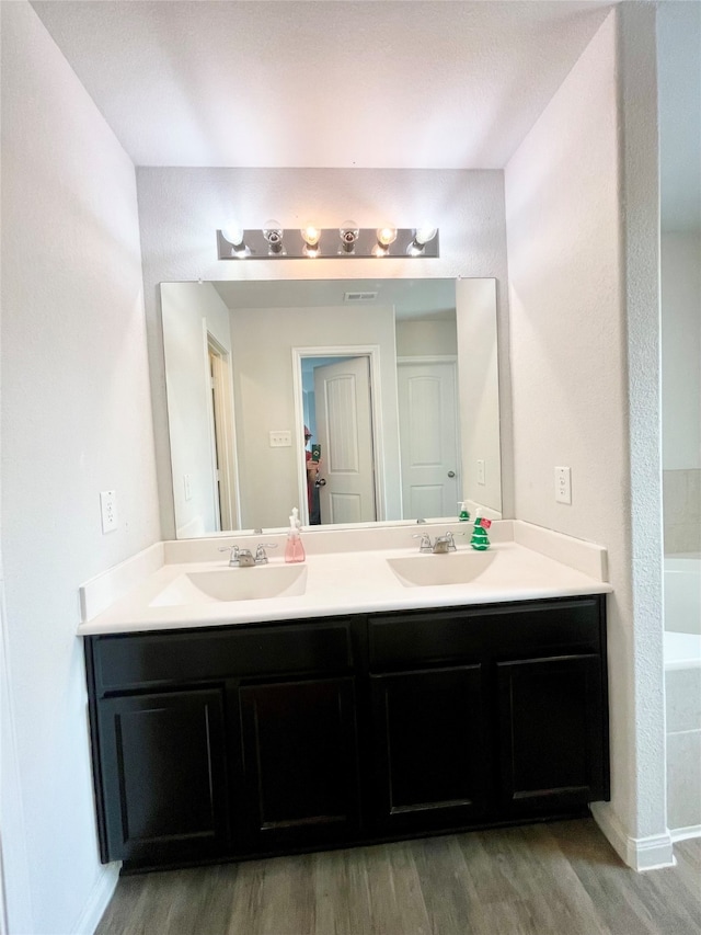 bathroom with vanity, hardwood / wood-style floors, and a tub