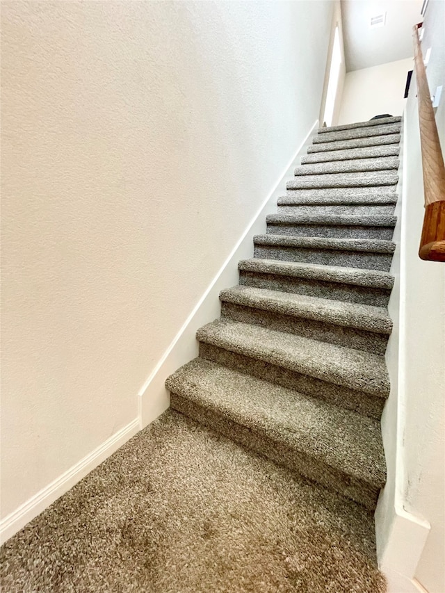 stairway featuring carpet flooring