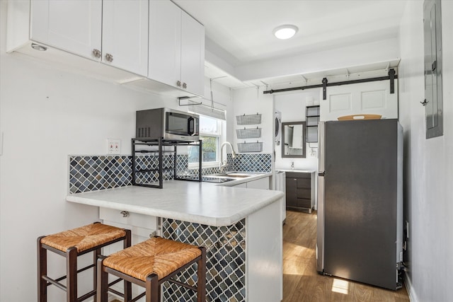 kitchen with a kitchen bar, white cabinetry, light wood-type flooring, and appliances with stainless steel finishes