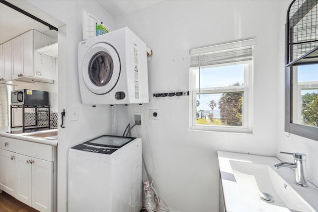 laundry area with dark hardwood / wood-style flooring, water heater, sink, and stacked washer / drying machine