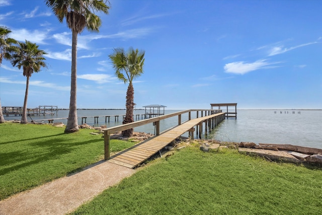 view of dock with a lawn and a water view