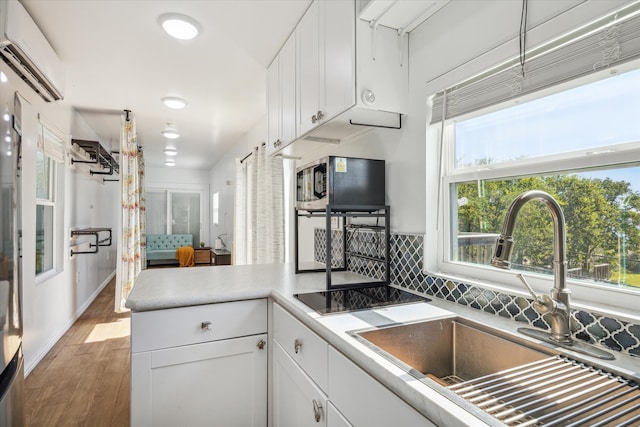 kitchen featuring sink, white cabinets, a wall mounted air conditioner, and hardwood / wood-style flooring