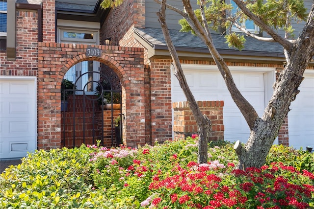 7109 Broadway St, Galveston, TX 77554 - doorway to property featuring brick siding, a shingled roof, and a garage