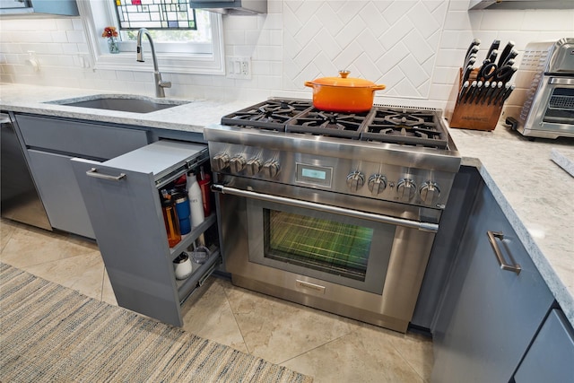 7109 Broadway St, Galveston, TX 77554 - kitchen with light stone countertops, stainless steel stove, tasteful backsplash, a sink, and gray cabinetry
