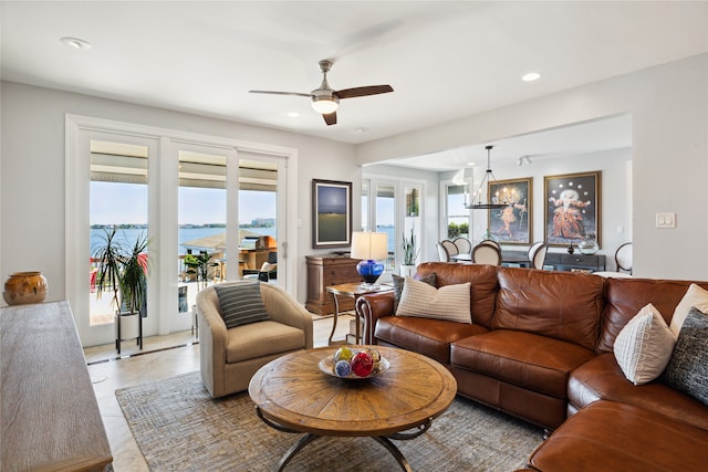 living room with a water view and ceiling fan with notable chandelier