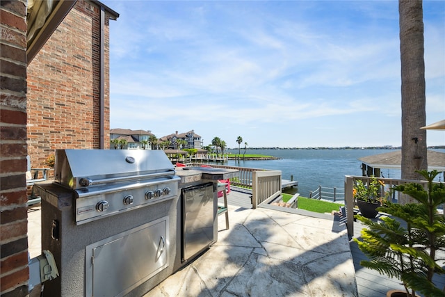 view of patio featuring a water view, grilling area, and exterior kitchen