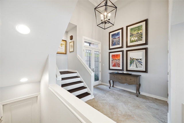 staircase featuring french doors, lofted ceiling, and an inviting chandelier