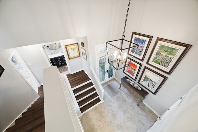 staircase featuring a notable chandelier, hardwood / wood-style floors, and a high ceiling