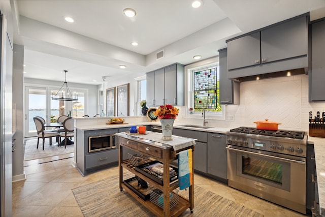 kitchen featuring decorative backsplash, hanging light fixtures, gray cabinetry, stainless steel appliances, and sink