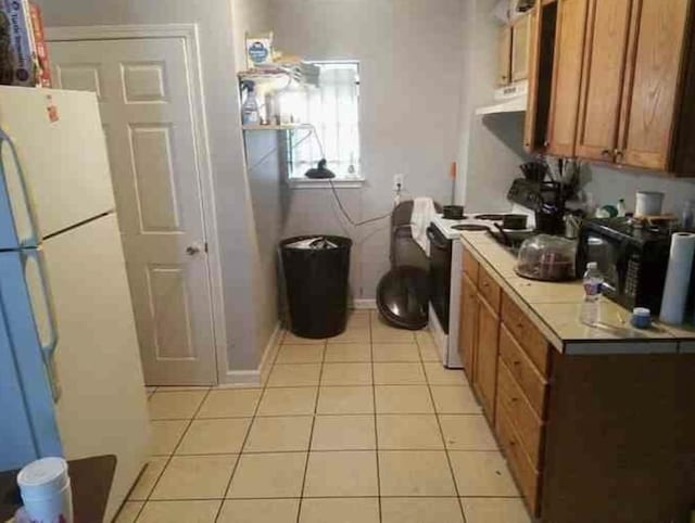 6516 Sidney St Unit A, Houston, TX 77021 - kitchen featuring ventilation hood, brown cabinetry, electric stove, freestanding refrigerator, and light tile patterned floors
