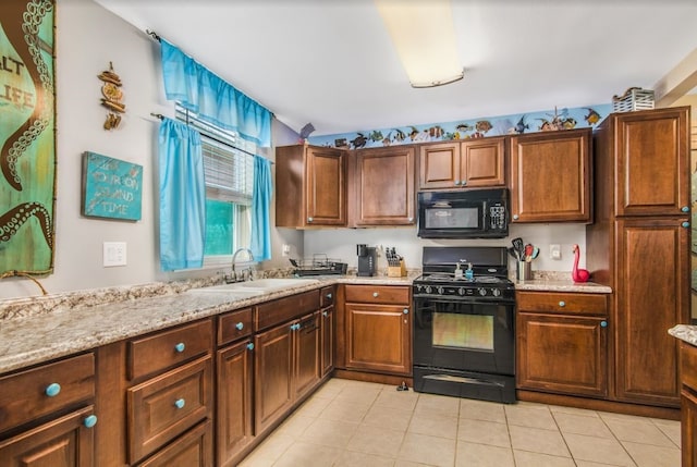 kitchen featuring black appliances, light stone countertops, sink, and light tile patterned floors