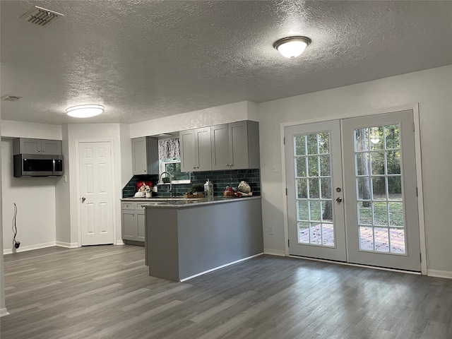 kitchen with gray cabinets, a textured ceiling, kitchen peninsula, and wood-type flooring