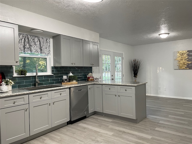 kitchen with sink, a wealth of natural light, dishwasher, and kitchen peninsula