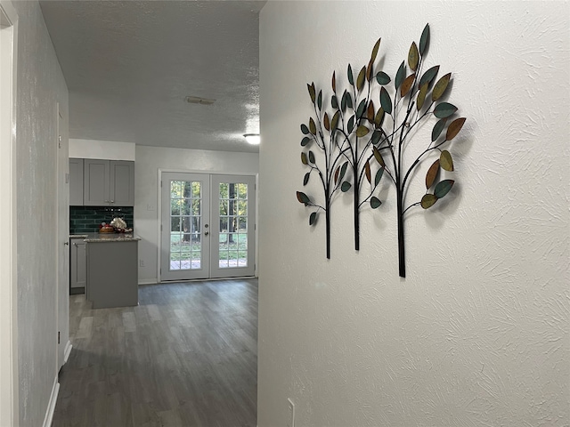 hallway with french doors, a textured ceiling, and dark hardwood / wood-style flooring