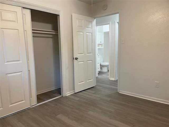 unfurnished bedroom with a closet and dark hardwood / wood-style flooring