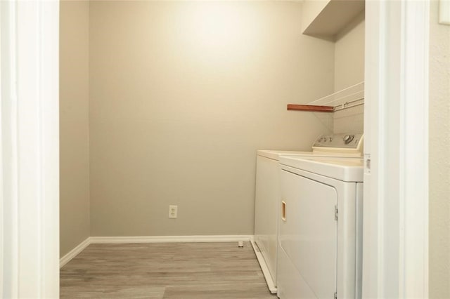 laundry area with light hardwood / wood-style flooring and washer and dryer