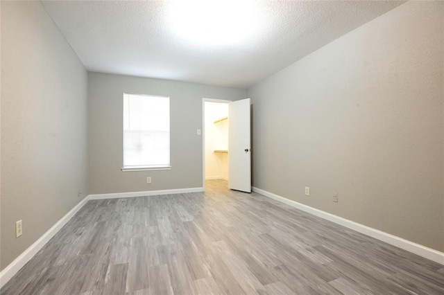 empty room featuring a textured ceiling and light hardwood / wood-style flooring