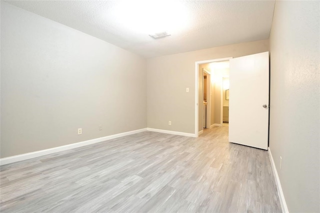 unfurnished room featuring light hardwood / wood-style floors and a textured ceiling