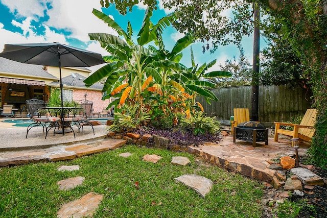 view of yard featuring a patio area, fence, a fire pit, and outdoor dining space