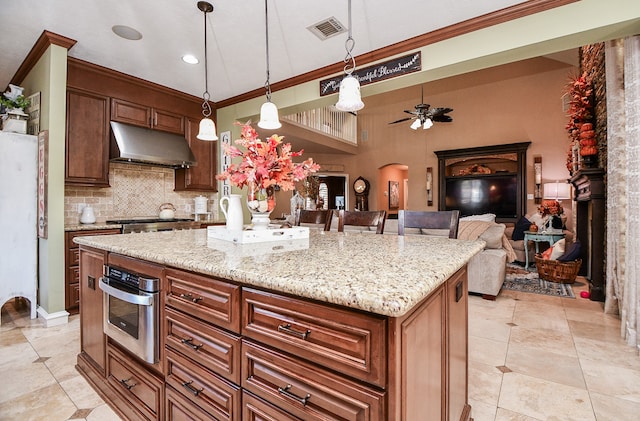 kitchen with arched walkways, under cabinet range hood, visible vents, appliances with stainless steel finishes, and backsplash