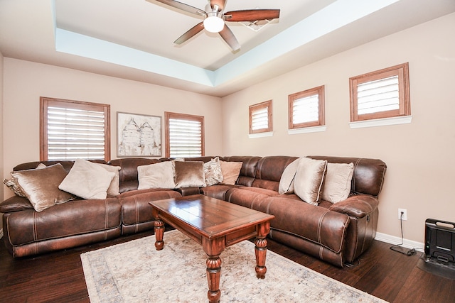 living room featuring a ceiling fan, baseboards, a raised ceiling, and dark wood-type flooring