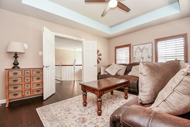 living area featuring a tray ceiling, dark wood finished floors, and ceiling fan