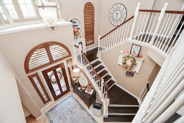 foyer with a towering ceiling, stairs, baseboards, and french doors