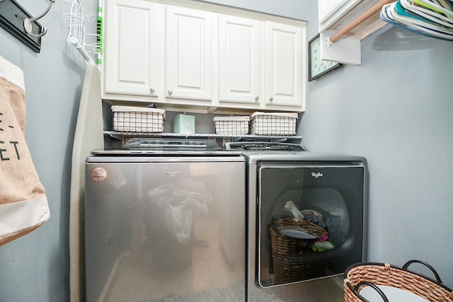 clothes washing area featuring washing machine and dryer and cabinet space