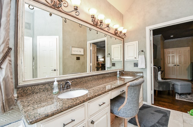 ensuite bathroom with double vanity, connected bathroom, a sink, and tile patterned floors