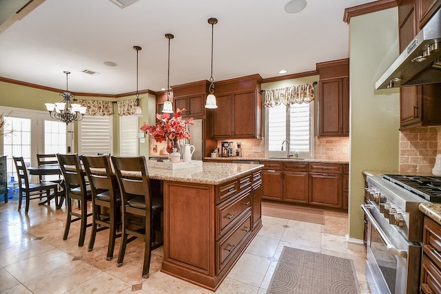 kitchen featuring stainless steel range, visible vents, a kitchen island, range hood, and a sink