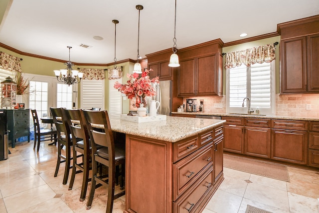 kitchen with a sink, visible vents, ornamental molding, stainless steel refrigerator, and tasteful backsplash