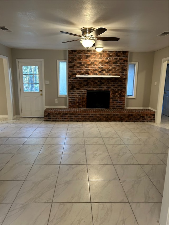 unfurnished living room with ceiling fan and a brick fireplace