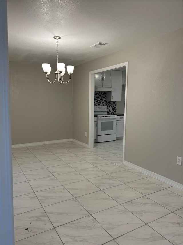 spare room featuring a notable chandelier and a textured ceiling