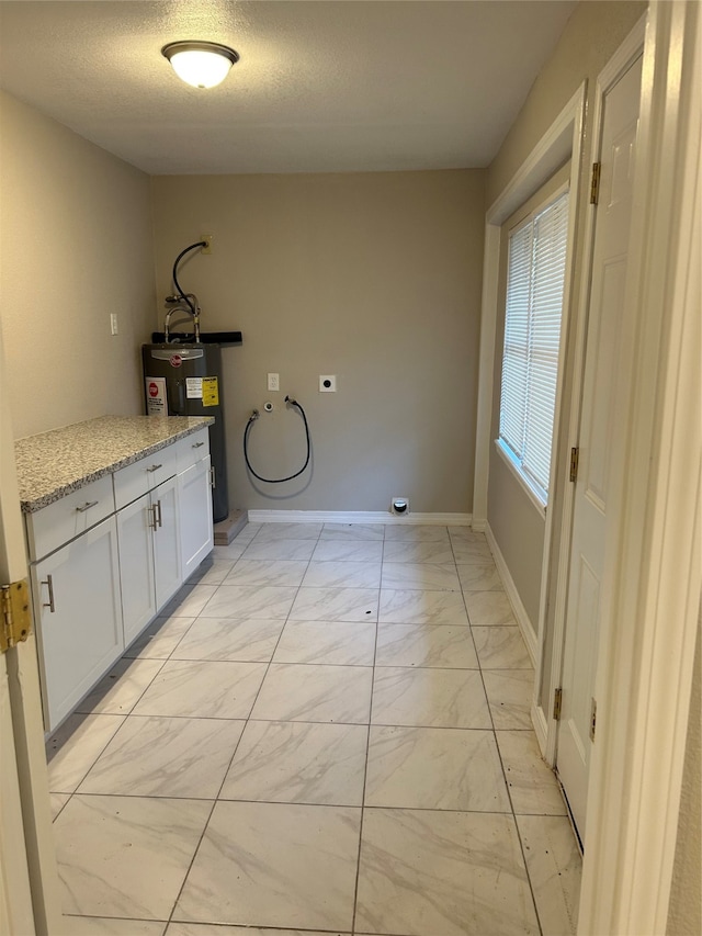 clothes washing area featuring electric water heater, hookup for a washing machine, hookup for an electric dryer, cabinets, and a textured ceiling