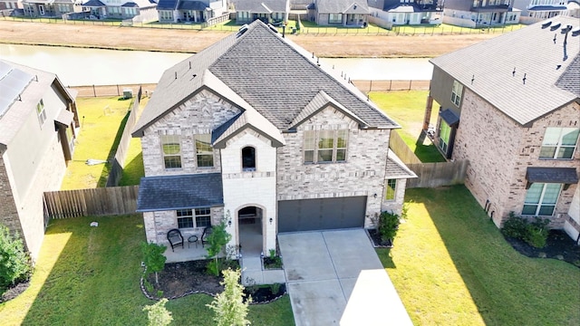 view of front of property featuring a garage, a water view, and a front lawn