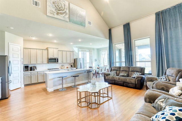 living room with light hardwood / wood-style flooring and high vaulted ceiling