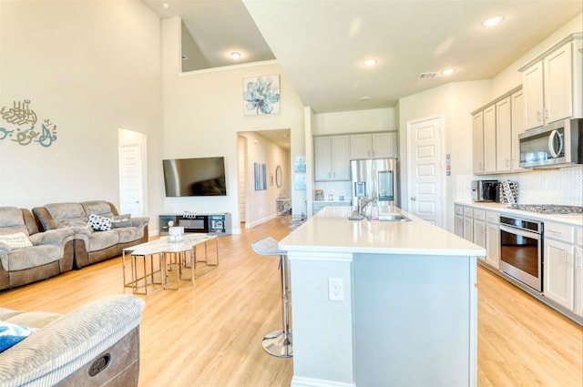 kitchen featuring a kitchen breakfast bar, light wood-type flooring, stainless steel appliances, and a kitchen island with sink