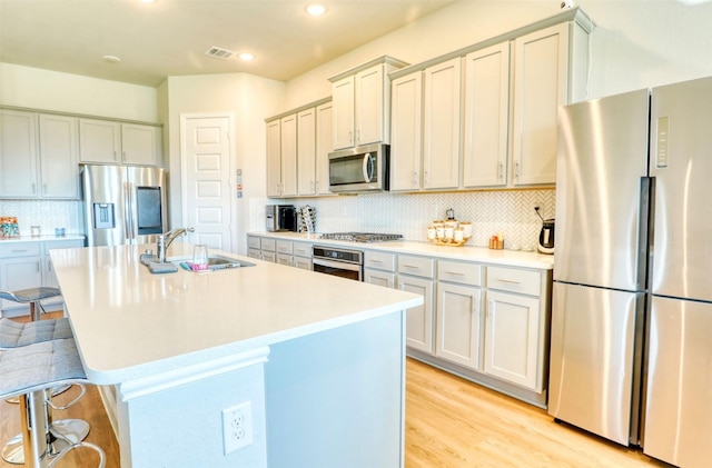 kitchen featuring appliances with stainless steel finishes, a kitchen island with sink, a kitchen breakfast bar, and sink